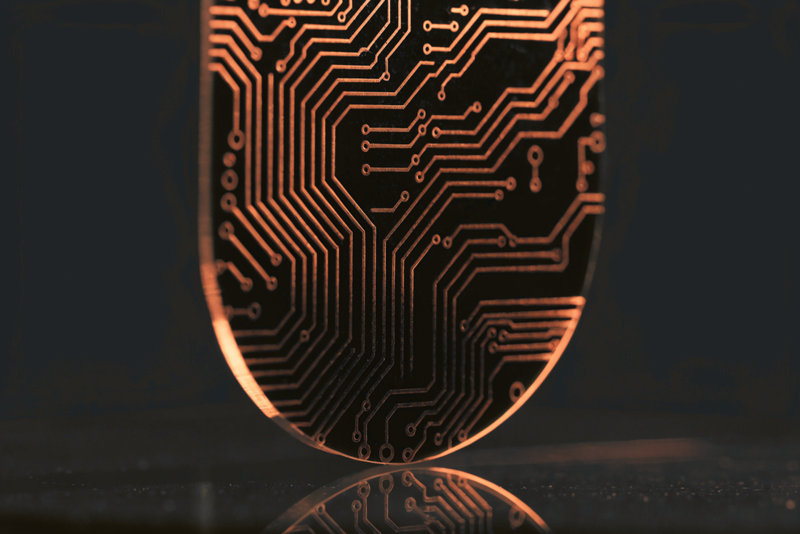 Bare circuit board with copper traces in warm amber light