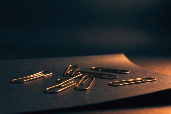 Brass paper clips on dark paper
