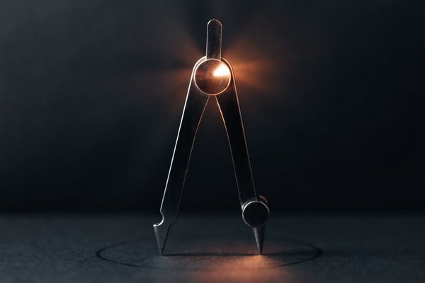 A drafting compass on dark paper